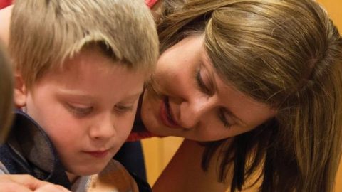 A mother and son work on an art project with paint.