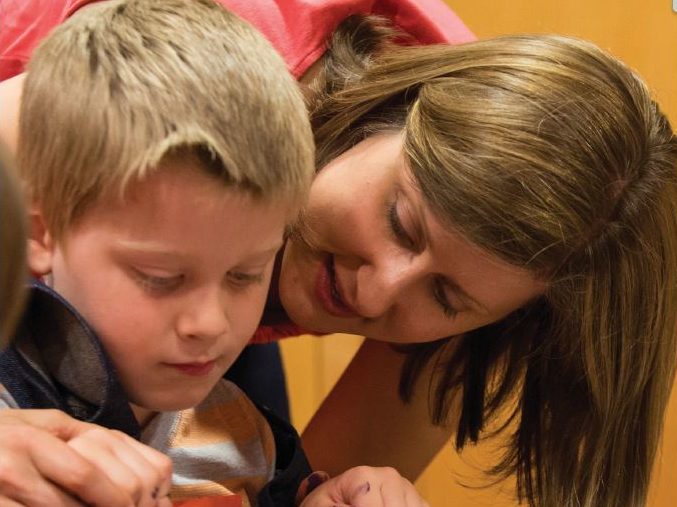 A mother and son work on an art project with paint.