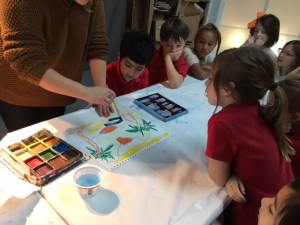 A teacher shows several students how to paint a landscape painting.