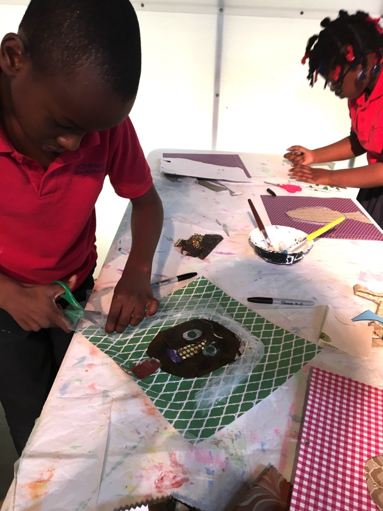 A young boy cutting his portrait of a woman.