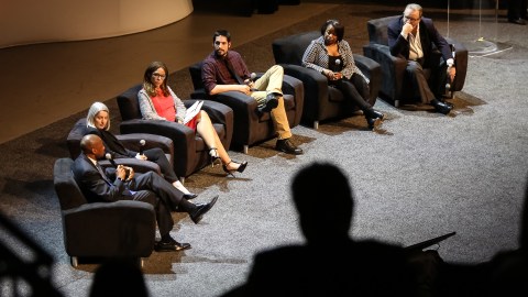 Six people sitting in chairs on a stage