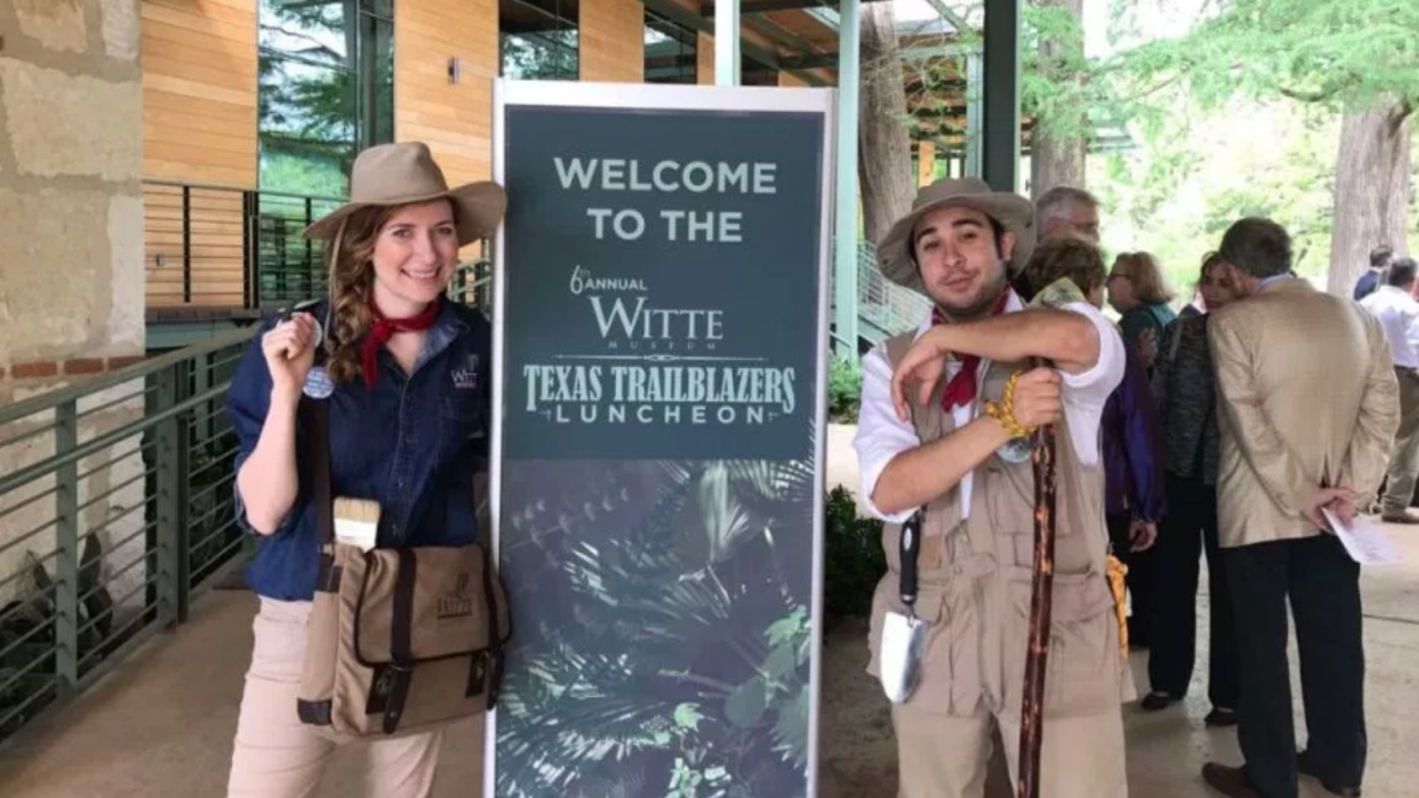 A female and a male staff member pose alongside a sign for Texas Trailblazers