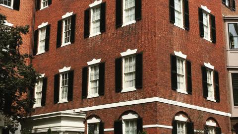View of courtyard entrance to a red brick building with black shutters.