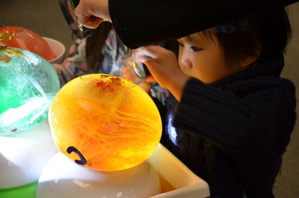 Young child examining a glowing orb closely