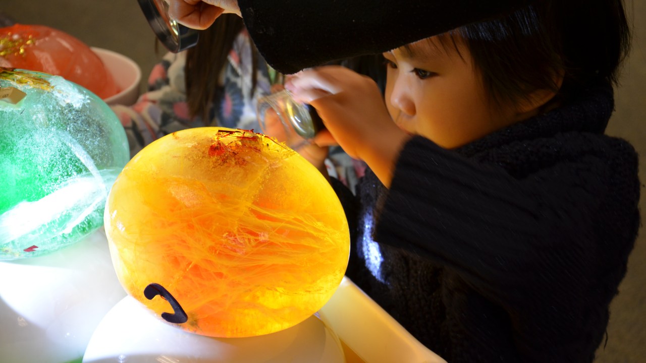Young child examining a glowing orb closely