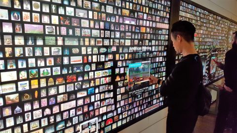 A person browsing from a large digital screen with images of objects
