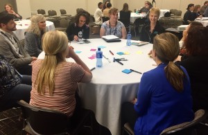 Group of people sitting around a table with multi-colored Post-It notes