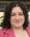 Image of woman with curly short dark colored hair smiling at the camera