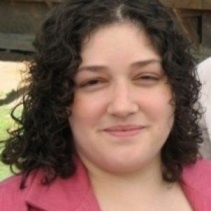 Image of woman with curly short dark colored hair smiling at the camera