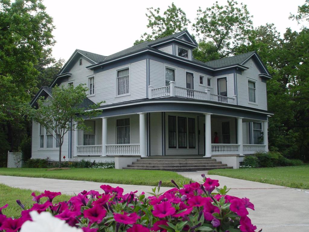 Exterior image of the front of the historic house two stories painted gray with a wrap around porch