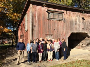 Group of 20 people standing in front of a rustic barn