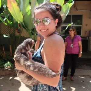 Gabriela smiling at the camera holding a real sloth