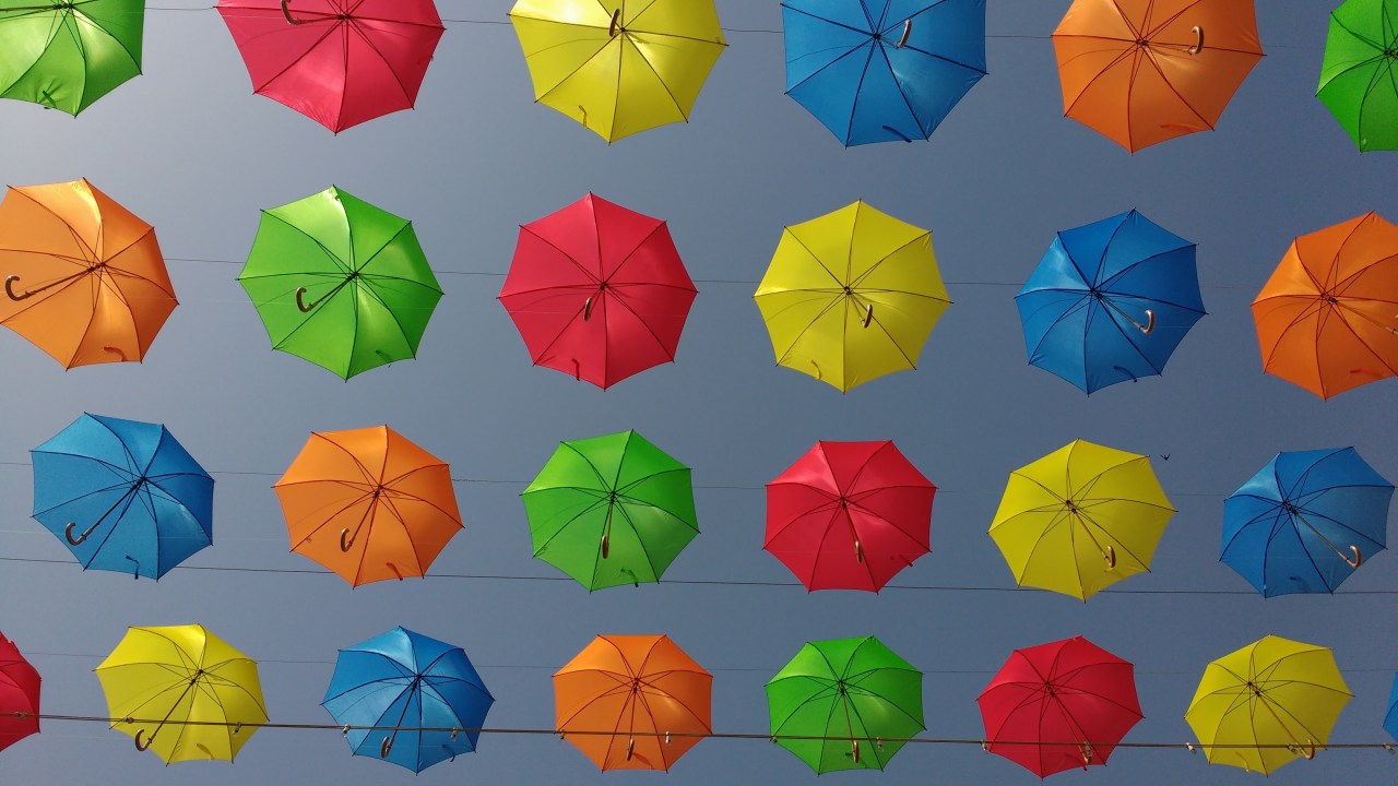 colorful umbrellas suspended in the sky and organized in a gridded pattern