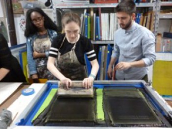 Three students work at a print station.