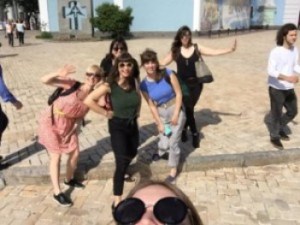 A group of women pose for the camera one just her sunglasses and the very tip of her forehead are visible.