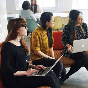 A group of workers sit on couches with laptops