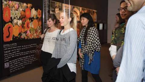 A group of people look at a picture on a wall smiling