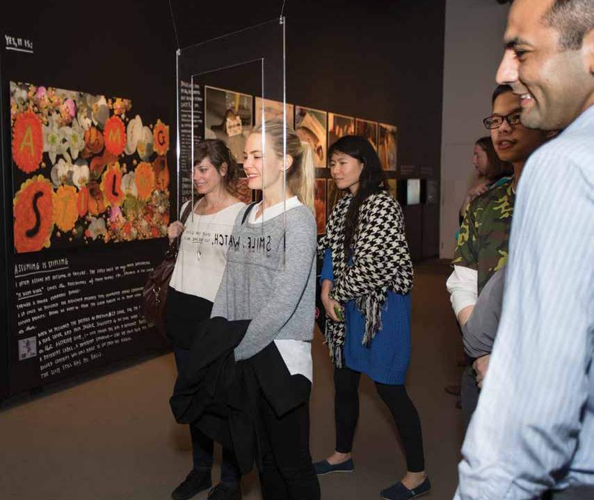 A group of people look at a picture on a wall smiling