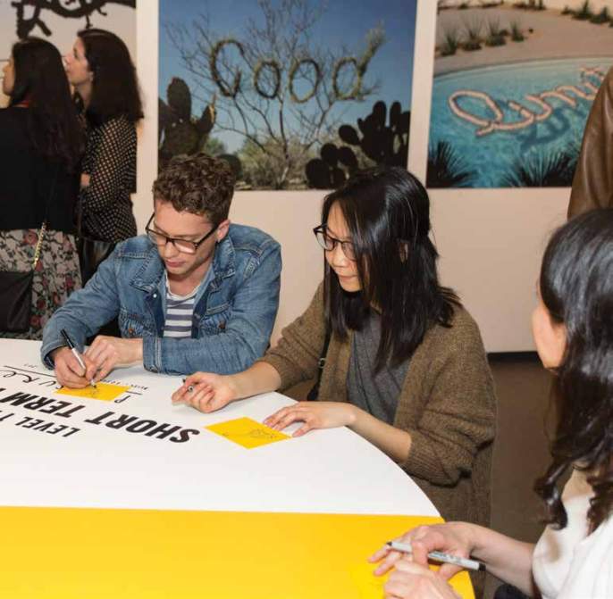 Three people sit at a table and write on Post-It notes