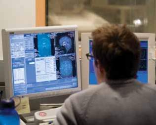 Image of a person reading a computer screen with a brain scan