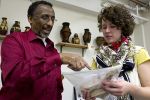 A man and a woman examine a piece of paper while standing in front of a group of shelves with various artifacts