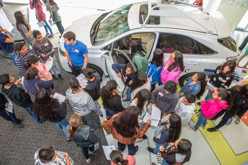 A group of young people gather around a car