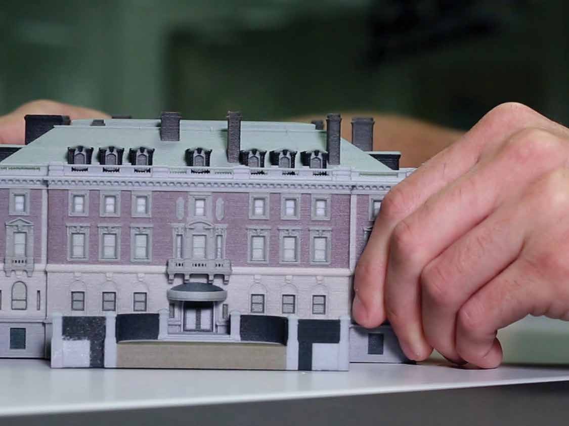Someone's hands manipulate a miniature building