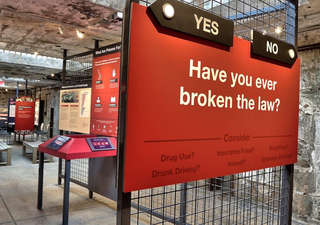 Image of a text panel in red with yes and no arrows pointing to different routes through the exhibit with the question "Have you ever broken the law?"