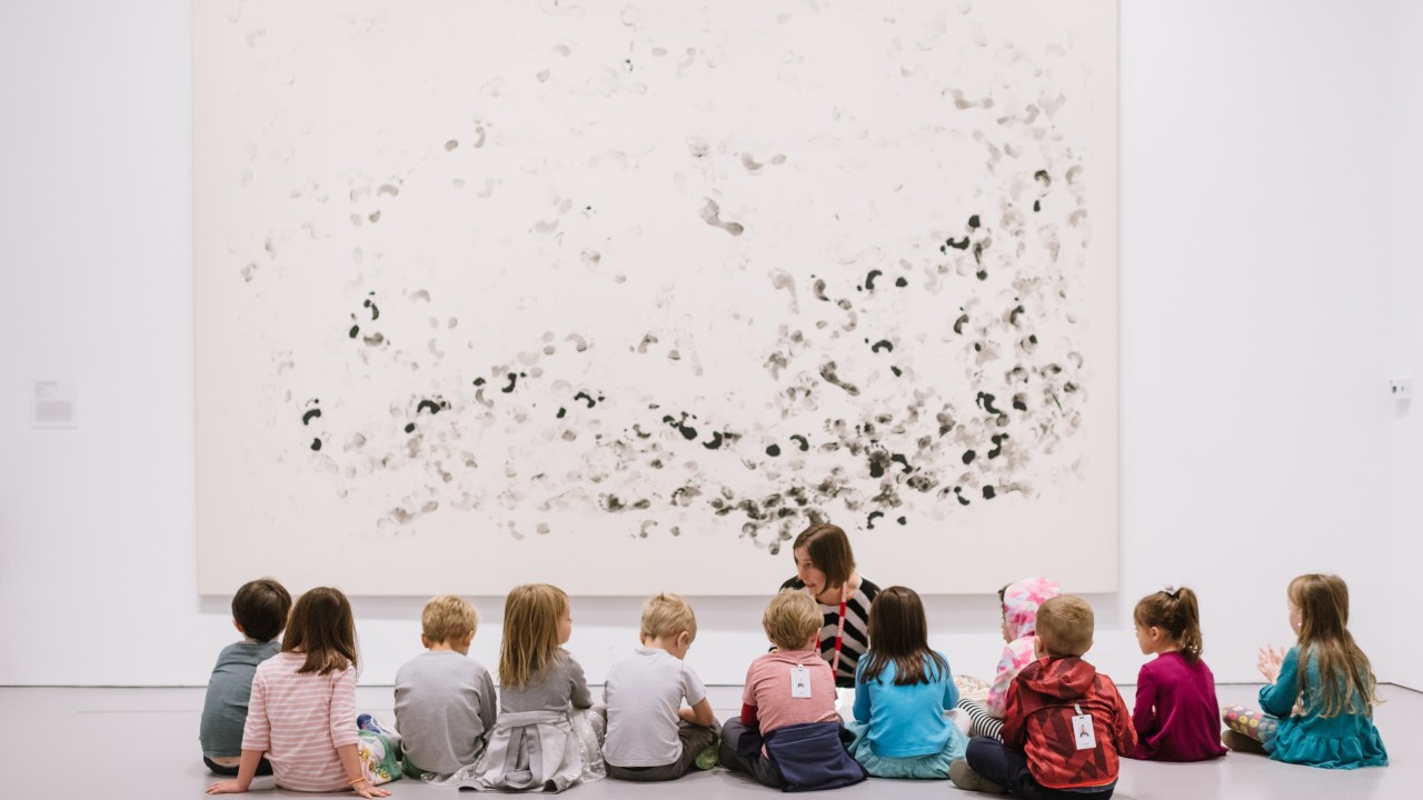 Group of small children sitting in front of an artwork in a museum gallery