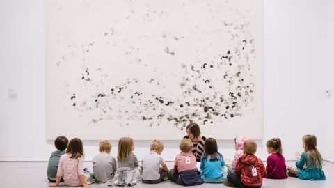 Group of small children sitting in front of an artwork in a museum gallery