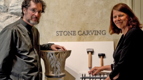 A man and a women standing together in front of a display with a column and stone carving tools