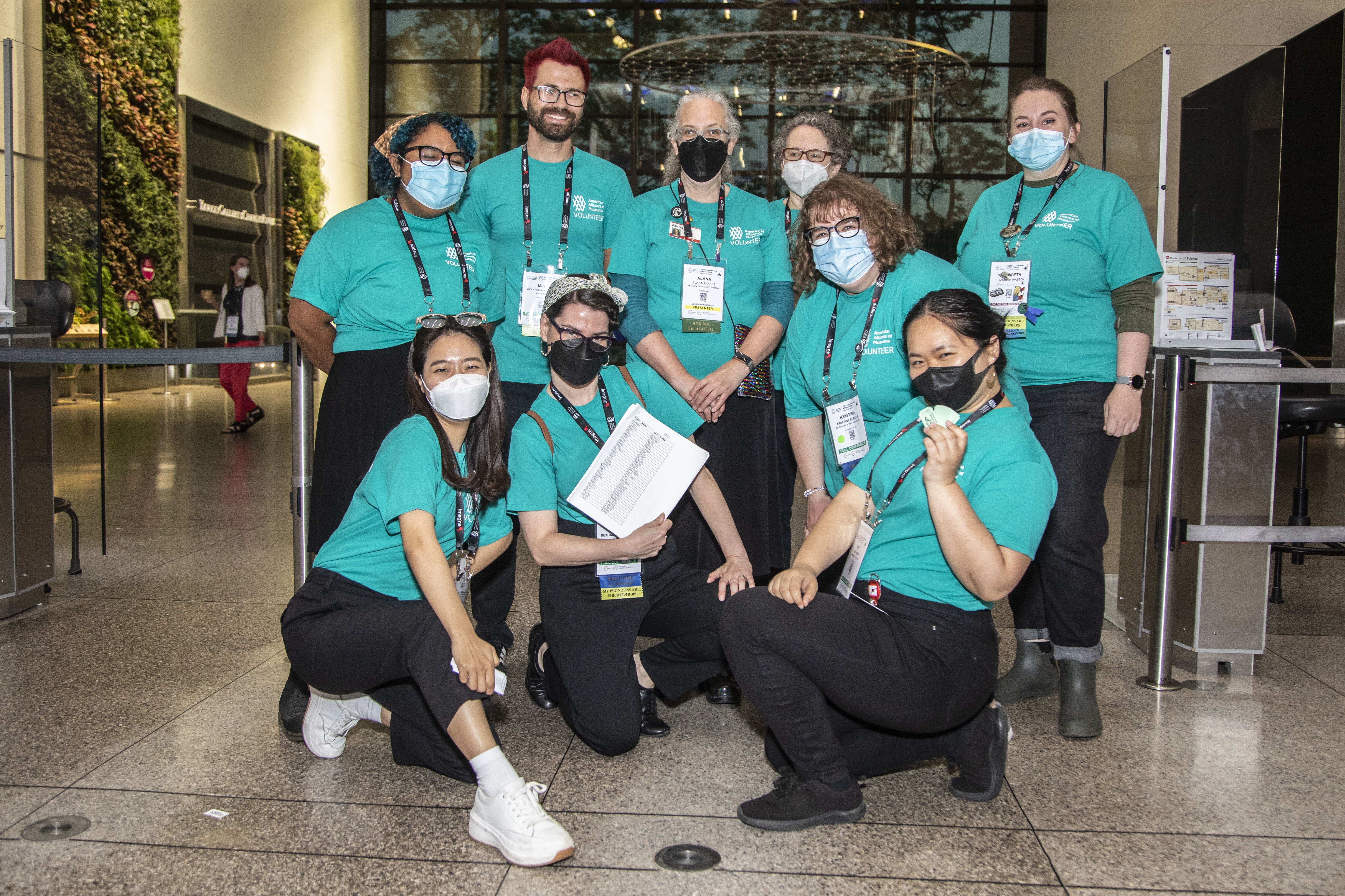 A group of volunteers smiling under face masks and posing for the camera