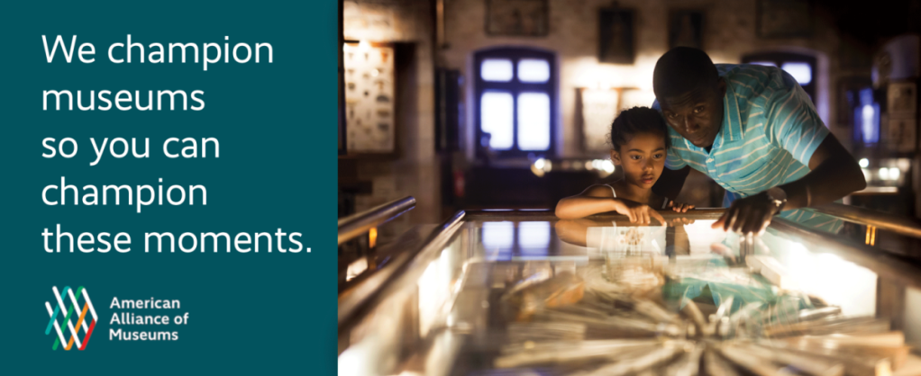 A father and daughter stand examining objects in a display case. Words to the left say, "We champion museums so you can champion these moments."