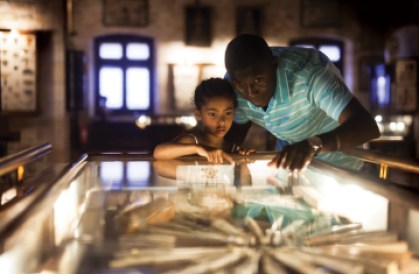 A father and daughter stand examining objects in a display case. Words to the left say, "We champion museums so you can champion these moments."