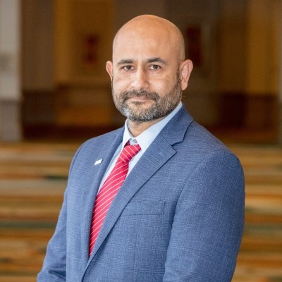 Headshot of Arminn Leopold. A bald man with a close shaven beard wearing a suit.