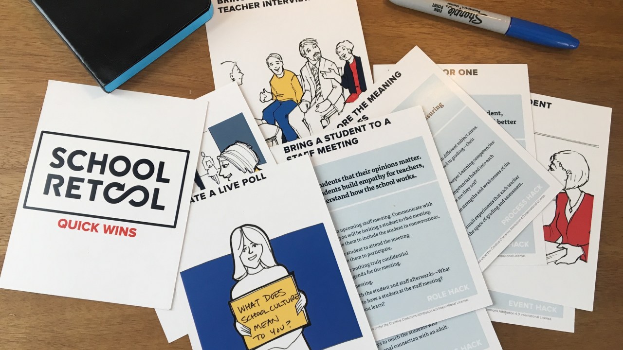 papers with illustrations scattered on the table. School Retool pamphlet along with a moleskine notebook and a sharpie marker