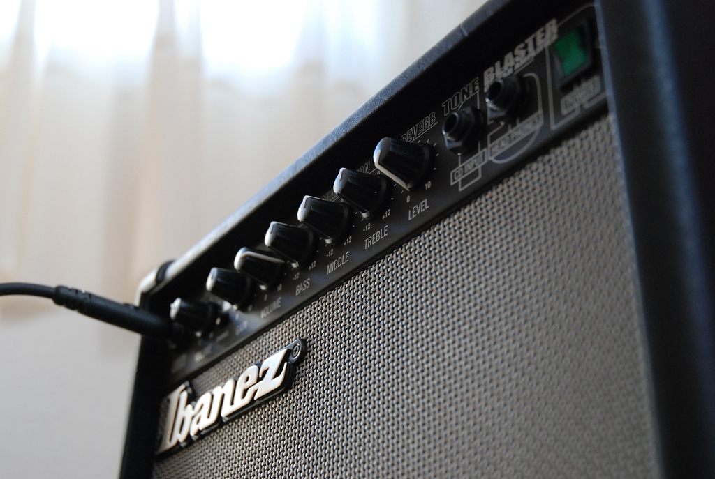 An Ibanez guitar amp with an cord plugged in and lots of dials