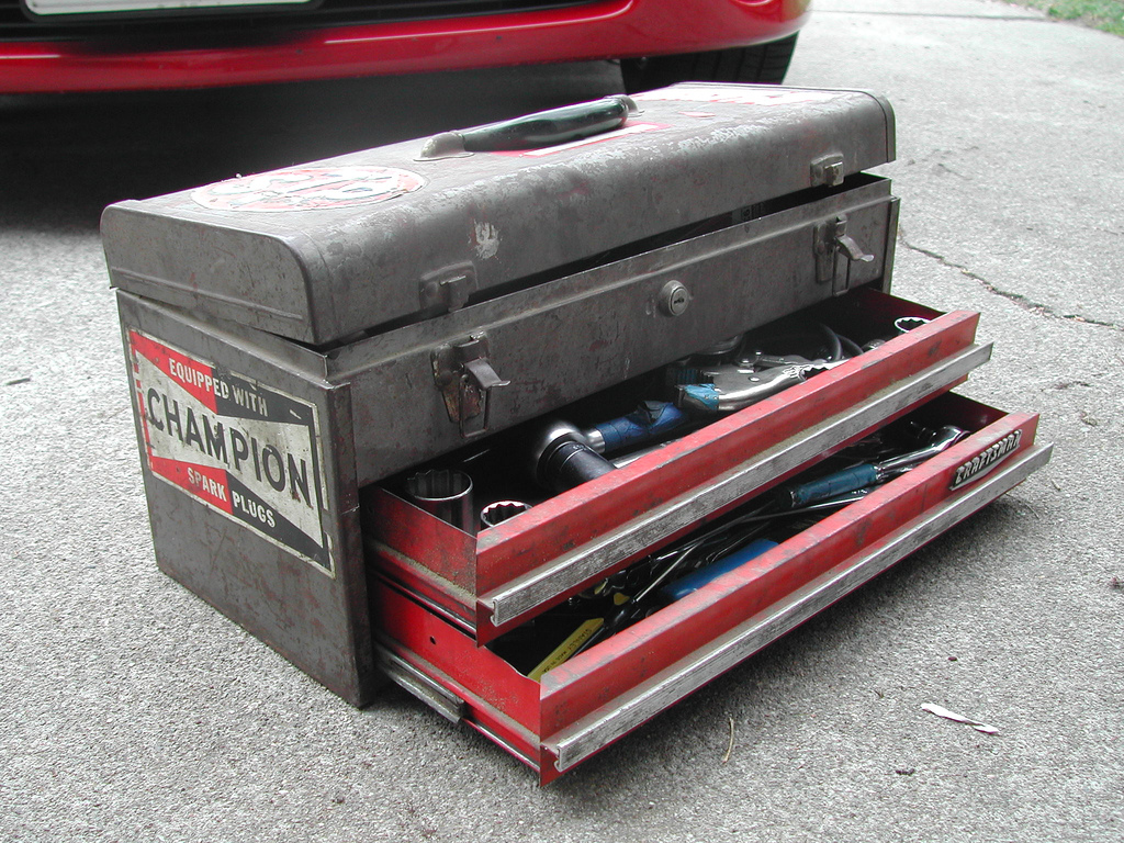 An old toolbox with a "champion" sticker on the side and two drawers partially open