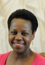Headshot of a black woman wearing dangling earrings with short cropped dark hair and wearing a pink top.