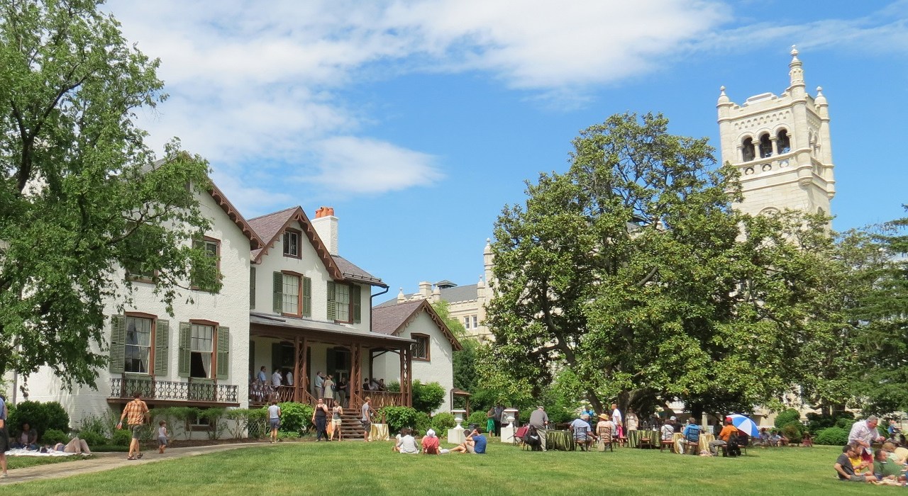 Image of the lawn and house with a group of people milling around.