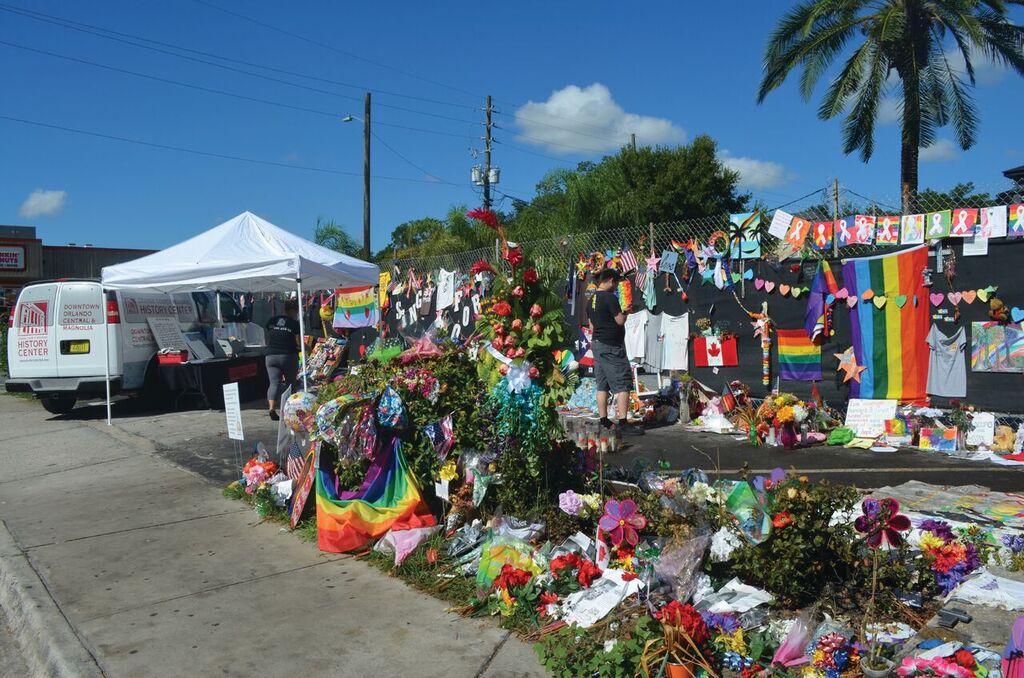 A colorful memorial of flowers and flags lines the sidewalk outside Pulse Nightclub.