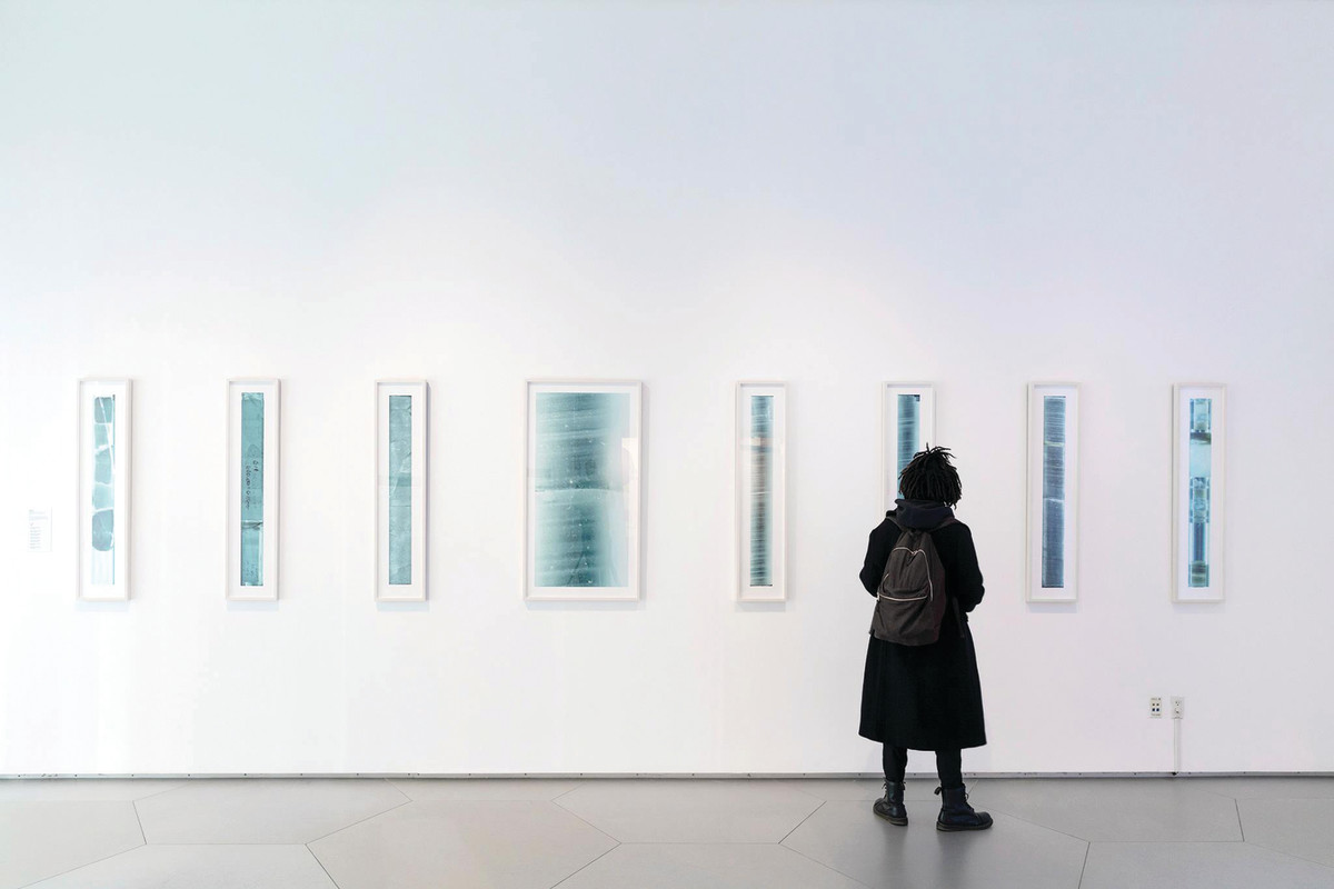 A woman looks at a wall with several pictures in blue.