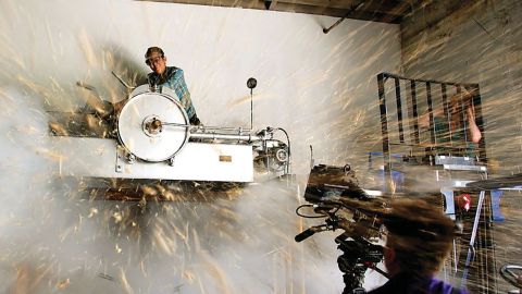View of a person working up high on a wall and sparks flying everywhere.