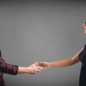 A blindfolded man and woman reach to shake hands with each other. This represents an unbiased hiring process.