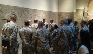 Soldiers gather around a carved wall to receive training on cultural property protection.