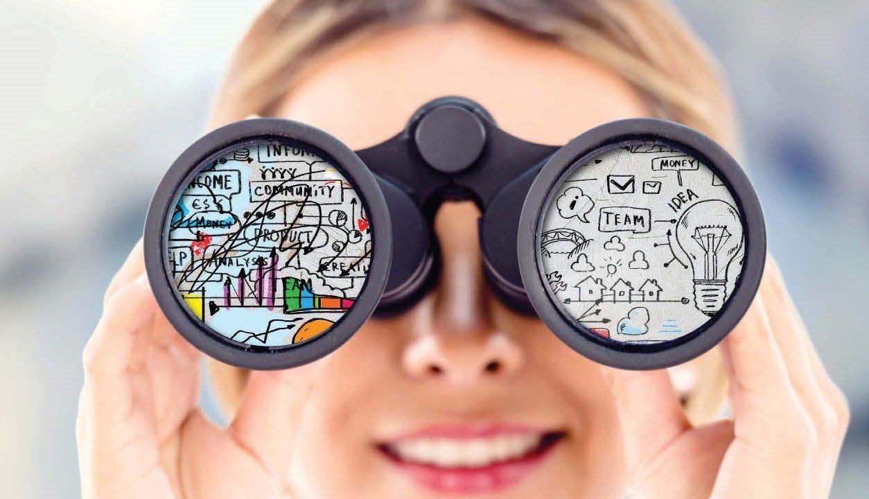 A woman looking through binoculars with various teambuilding terms on the glass.