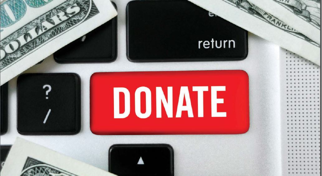 Closeup image of a keyboard with a red Donate button and cash laid over it.