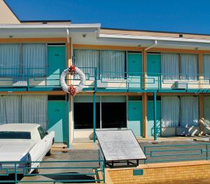Exterior shot of the Lorraine Motel with a large white wreath with red flowers at the top and bottom hung on the second floor railing. 