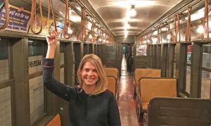 Meredith Gregory shown holding on to the handles in an empty subway car.