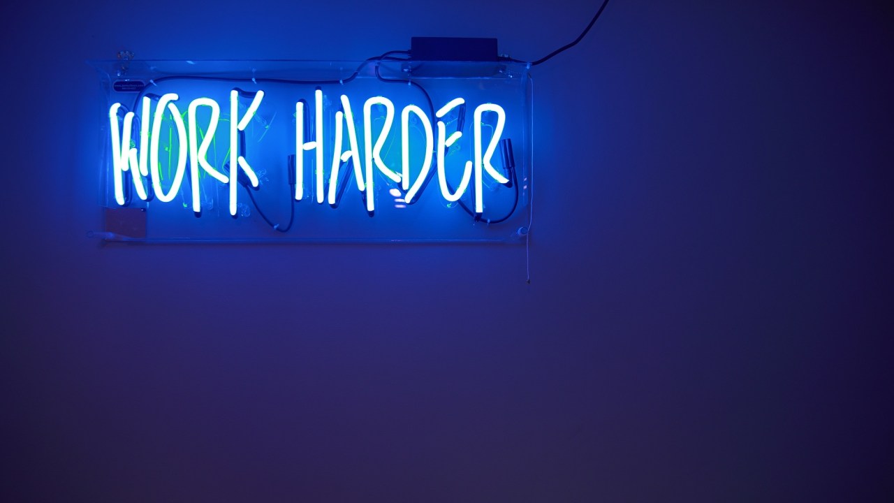 "Work Harder" neon sign hovers in the top left corner of this image.